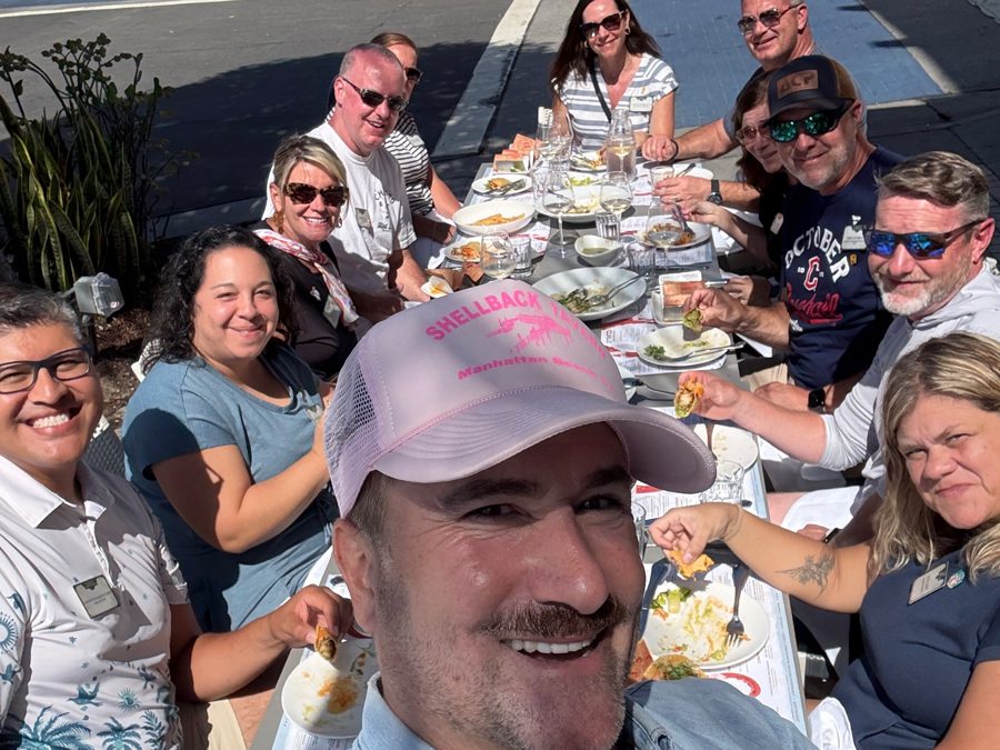 Brian taking a selfie with guests at a long outdoor table