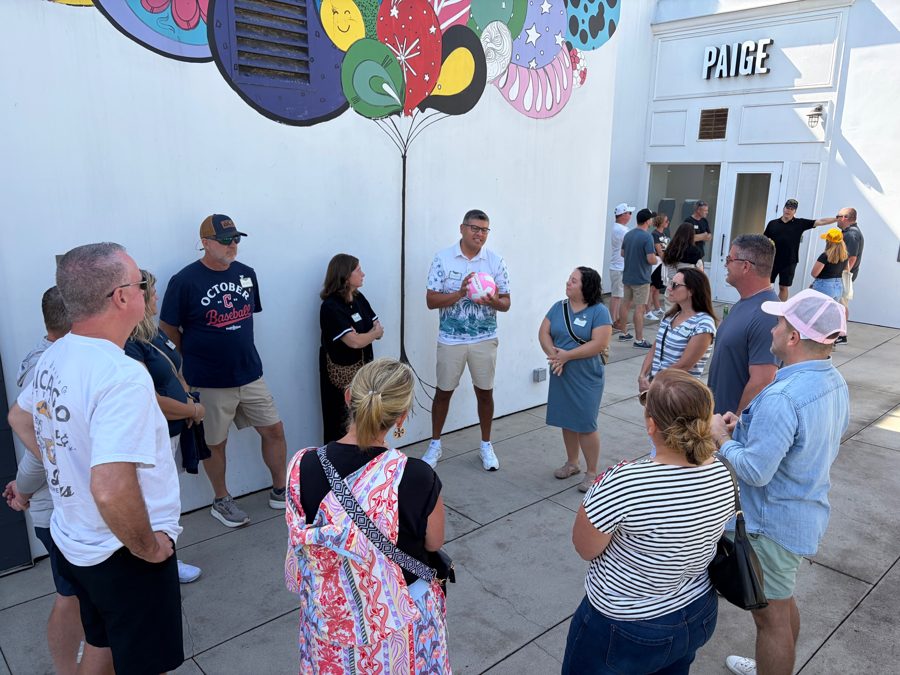 A tour group gathered beneath a colorful mural at Metlox Plaza