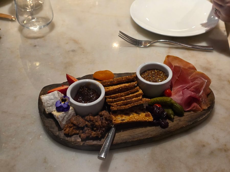 A charcuterie board with cheese, prosciutto, and jams